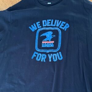 Men’s Black T-shirt with Vintage USPS Graphic We Deliver logo in blue and red.